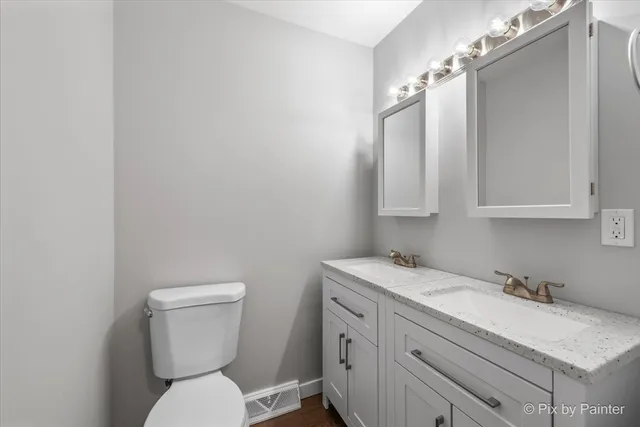 a bathroom with a granite countertop sink mirror vanity and toilet