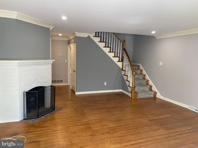 a view of an empty room with wooden floor a fireplace and a window
