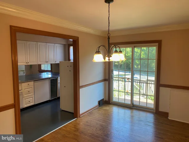 a kitchen with stainless steel appliances granite countertop a refrigerator a sink dishwasher a stove and a dining table with wooden floor