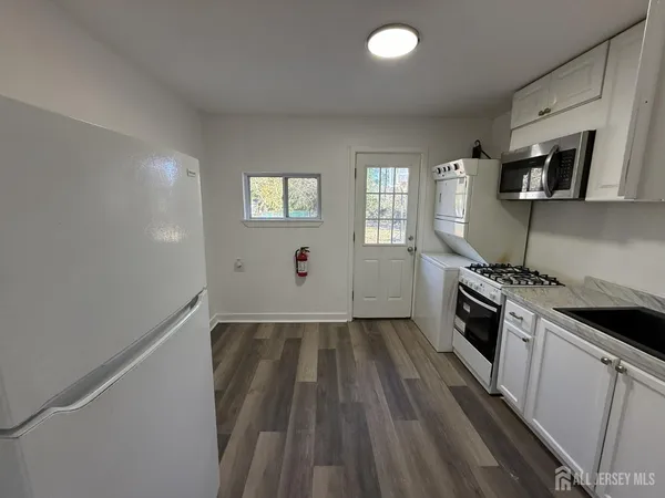 an empty room with wooden floor cabinet and windows