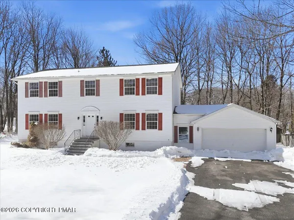 a front view of a house with a yard covered in snow