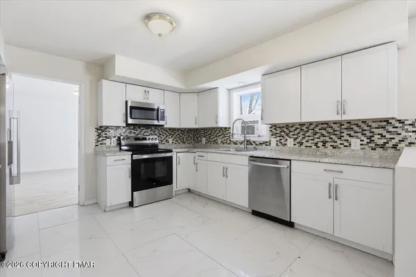 a kitchen with granite countertop white cabinets and stainless steel appliances