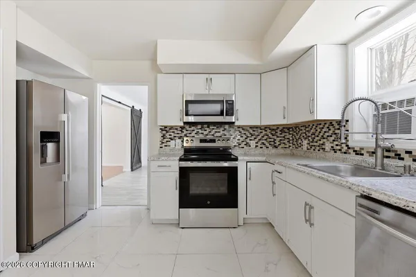 a kitchen with granite countertop white cabinets and stainless steel appliances