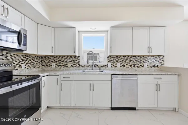 a kitchen with white cabinets and sink