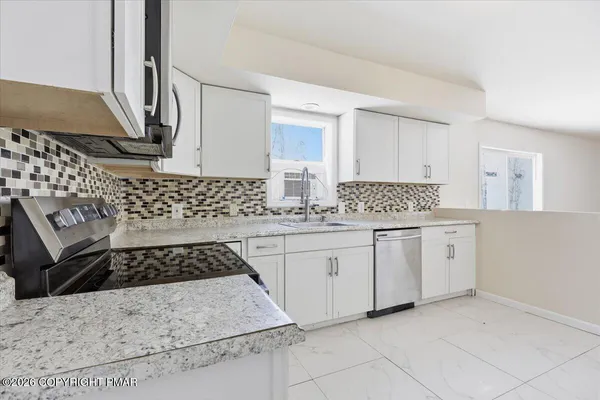 a kitchen with white cabinets a sink a stove and white stainless steel appliances