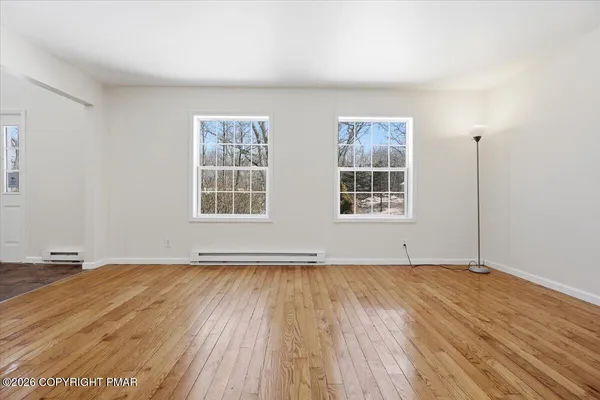 an empty room with wooden floor and windows