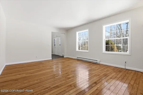 an empty room with wooden floor and windows