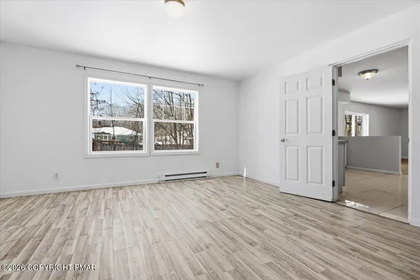 an empty room with wooden floor and windows
