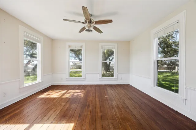 a view of empty room with wooden floor and fan