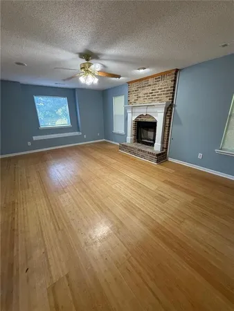an empty room with wooden floor fireplace and windows