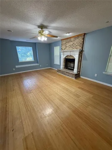 an empty room with wooden floor fireplace and windows