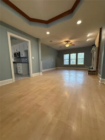a view of an empty room with wooden floor fireplace and a window