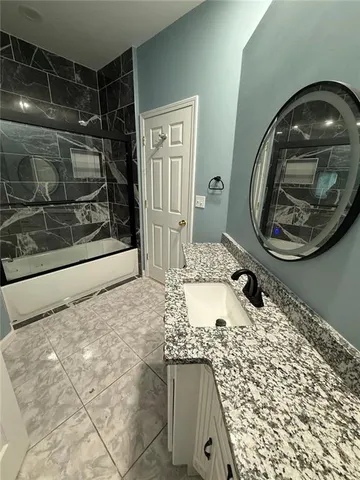 a bathroom with a granite countertop sink a mirror and shower