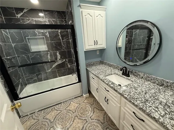 a bathroom with a granite countertop sink and a mirror