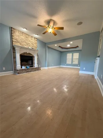 a view of an empty room with a fireplace and a chandelier fan