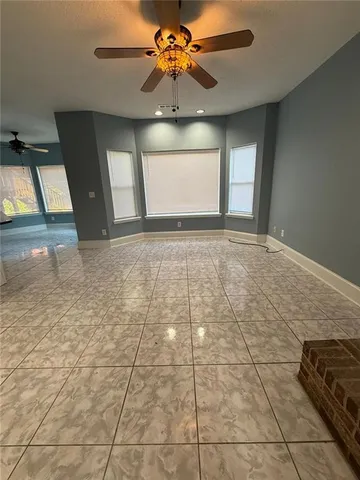 a view of empty room with window and chandelier fan