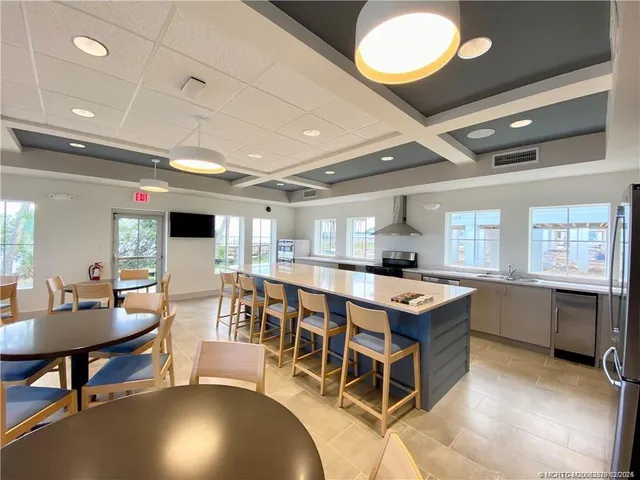 a room with stainless steel appliances kitchen island granite countertop a table chairs and a stove