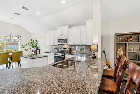 a view of a kitchen with kitchen island stainless steel appliances refrigerator stove top oven dining table and chairs