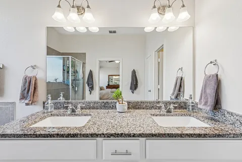a bathroom with double vanity sinks a vanity and a large mirror