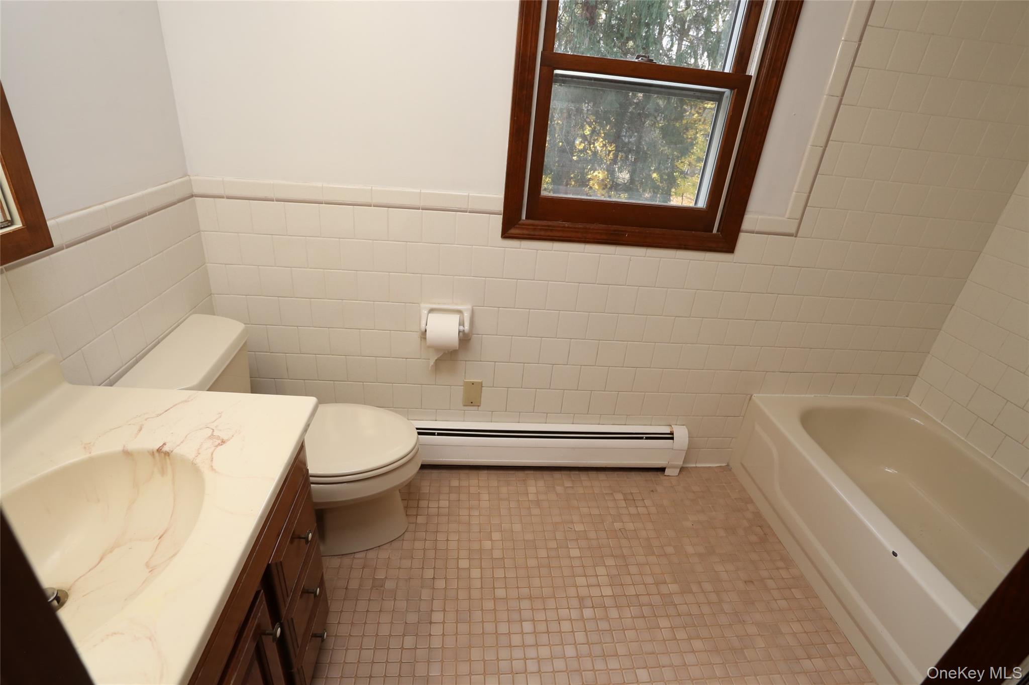 113 Brewery Road New City, NY 10956 - Photo 25 of 39 Bathroom featuring vanity, tile walls, a baseboard heating unit, wainscoting, and light tile patterned floors