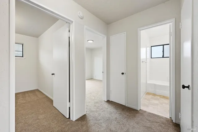 a view of an empty room with closet and a bathroom