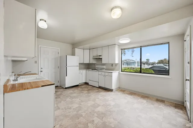 a large white kitchen with a refrigerator a sink and a cabinets