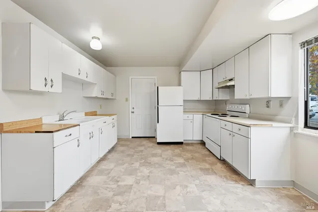 a kitchen with granite countertop white cabinets and white appliances