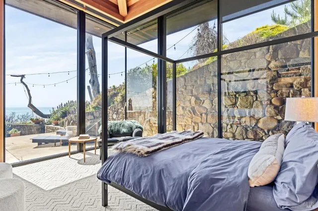 a bedroom with a bed and a large window with outer view