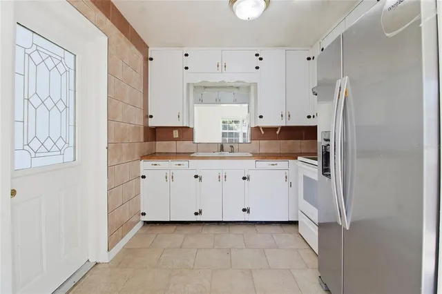a kitchen with granite countertop white cabinets and refrigerator