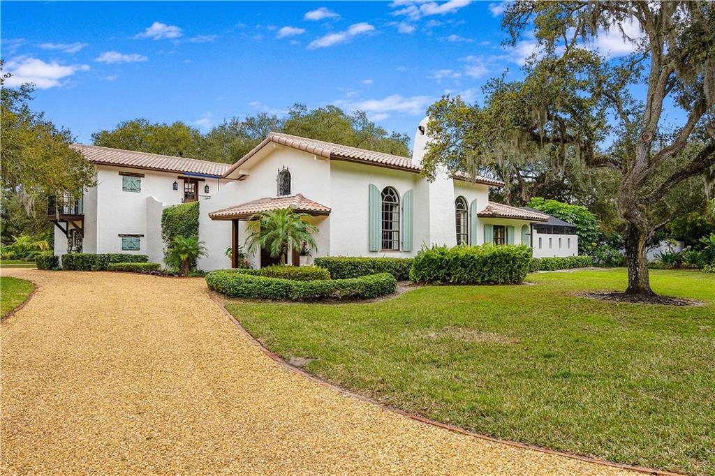 246 Live Oak Road Vero Beach, FL 32963 - Photo 2 of 30 a front view of a house with garden and trees