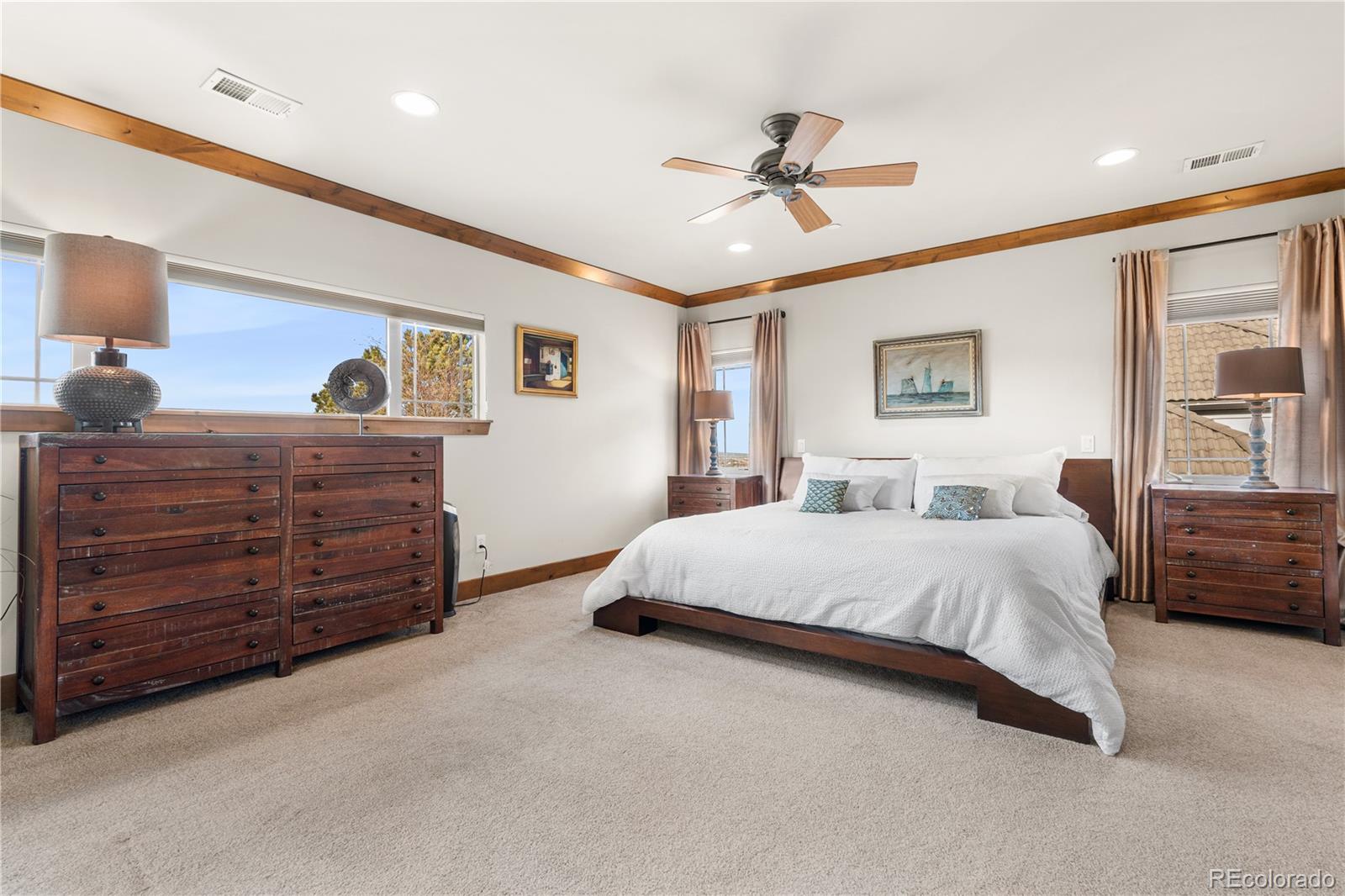 1251 Buffalo Ridge Road Castle Pines, CO 80108 - Photo 26 of 50 a spacious bedroom with a large bed and a chandelier