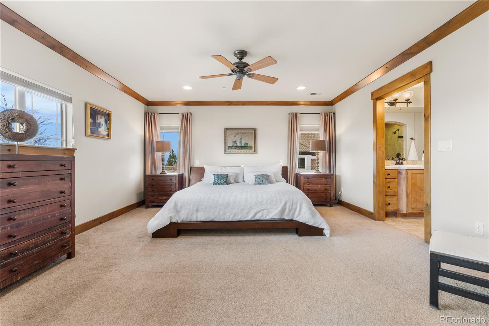 1251 Buffalo Ridge Road Castle Pines, CO 80108 - Photo 27 of 50 a spacious bedroom with a large bed and a chandelier