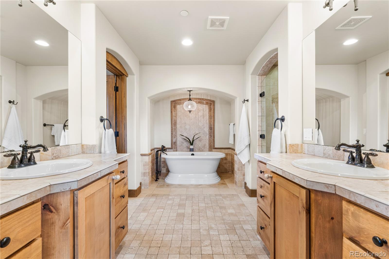 1251 Buffalo Ridge Road Castle Pines, CO 80108 - Photo 28 of 50 a spacious bathroom with a double vanity sink a mirror and a bathtub