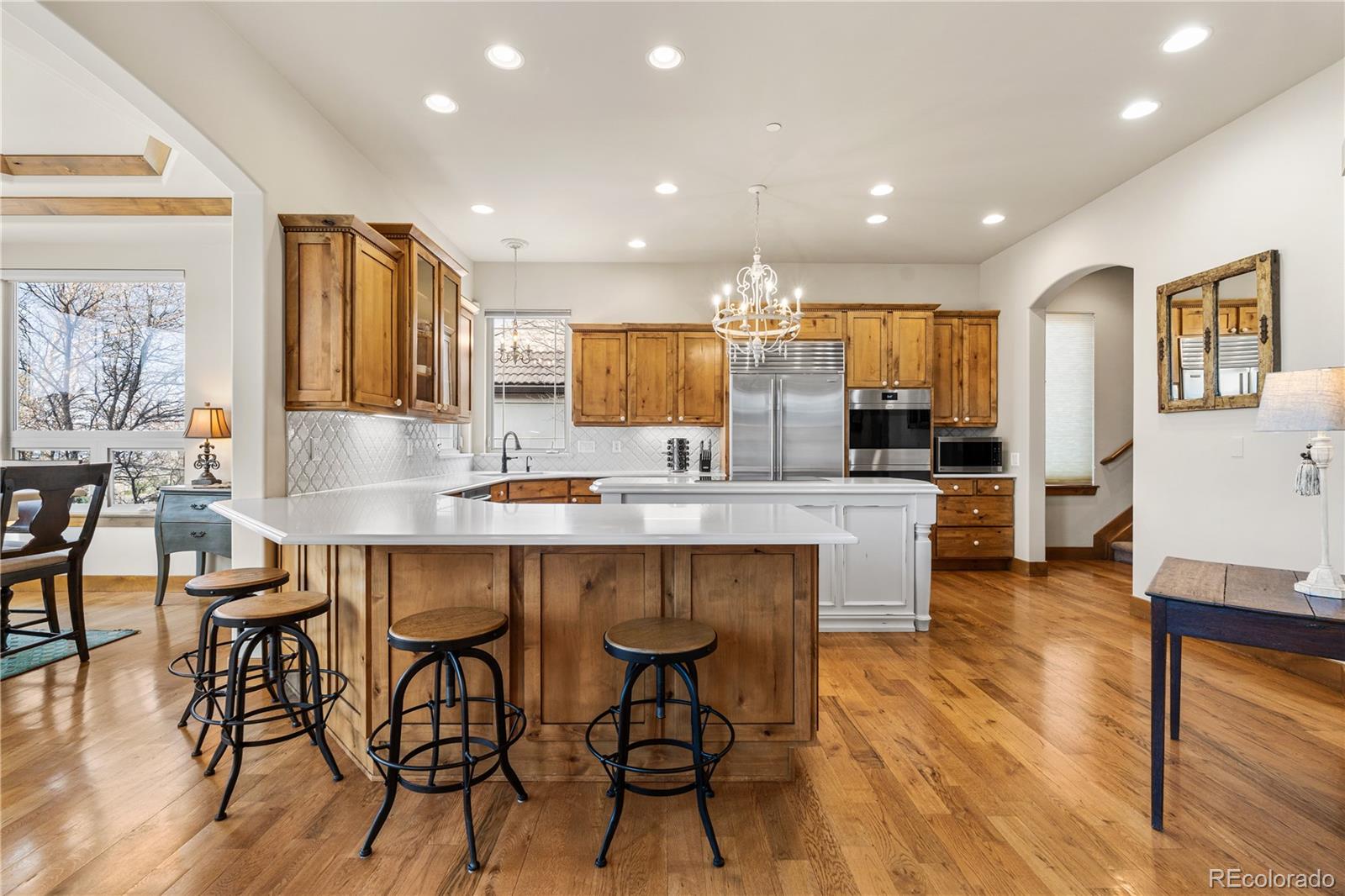 1251 Buffalo Ridge Road Castle Pines, CO 80108 - Photo 10 of 50 a kitchen with stainless steel appliances a dining table chairs and wooden floor