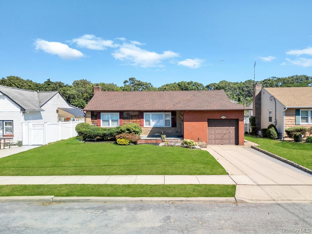 Single story home with concrete driveway, an attached garage, brick siding, a chimney, and roof with shingles