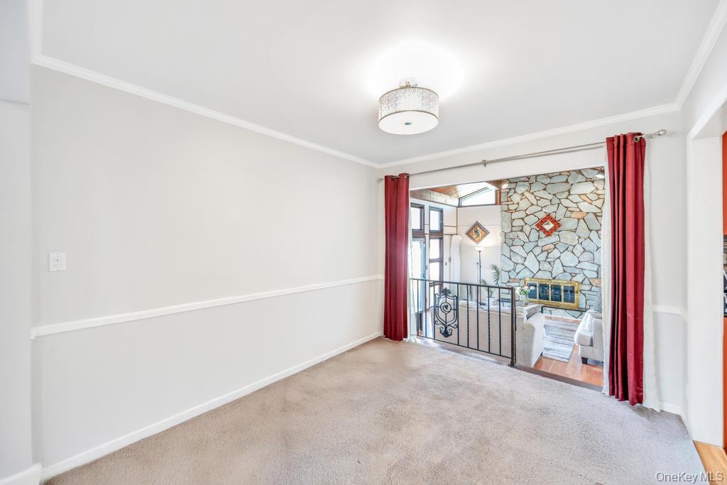 885 Downing Road Valley Stream, NY 11580 - Photo 18 of 36 Empty room featuring crown molding, carpet flooring, and a stone fireplace