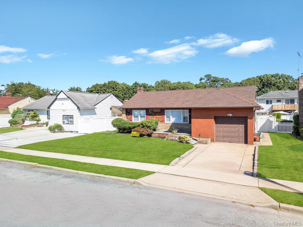 885 Downing Road Valley Stream, NY 11580 - Photo 2 of 36 Single story home featuring concrete driveway, an attached garage, brick siding, a chimney, and a residential view