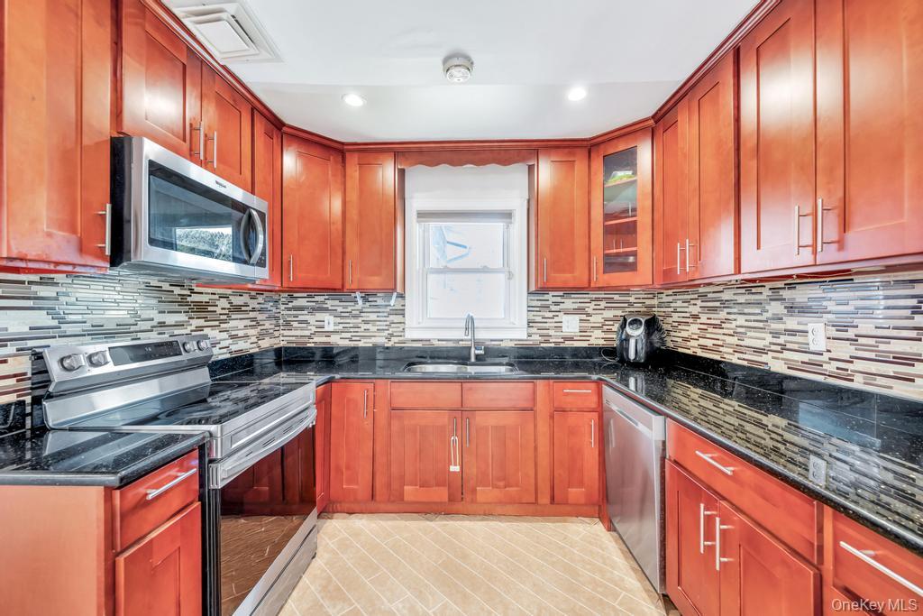 885 Downing Road Valley Stream, NY 11580 - Photo 22 of 36 Kitchen featuring stainless steel appliances, dark stone counters, backsplash, glass insert cabinets, and recessed lighting
