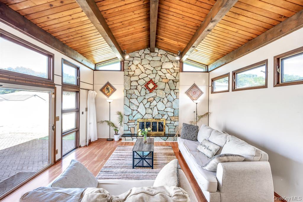 885 Downing Road Valley Stream, NY 11580 - Photo 25 of 36 Living area featuring light wood-style flooring, a stone fireplace, a wooden ceiling with exposed beams, and high vaulted ceiling