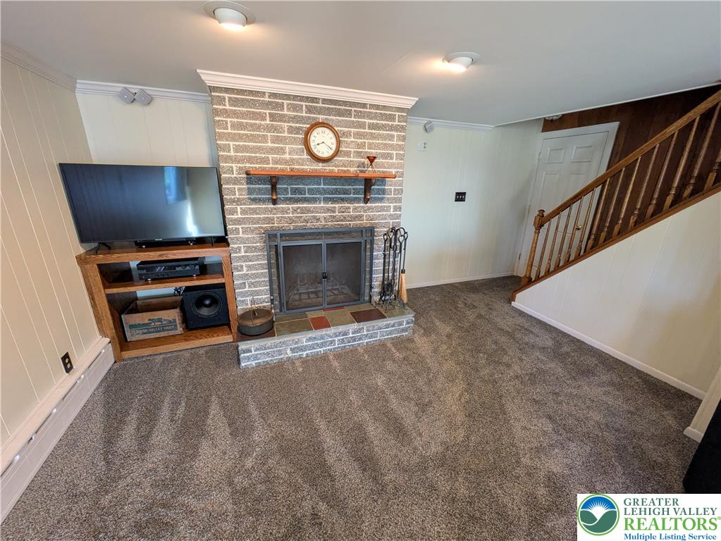 3285 Cherryville Road Northampton, PA 18067 - Photo 32 of 51 A classic brick fireplace anchors this carpeted living space framed by a wooden staircase.