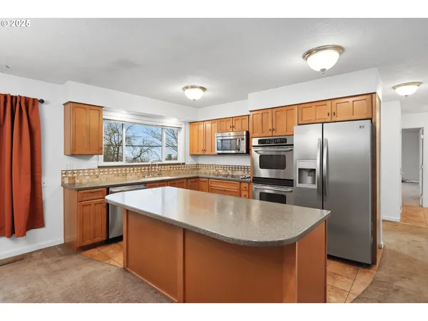 a kitchen with stainless steel appliances granite countertop a sink a stove and a refrigerator