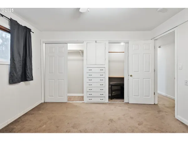 a view of an empty room with cabinet and mirrors