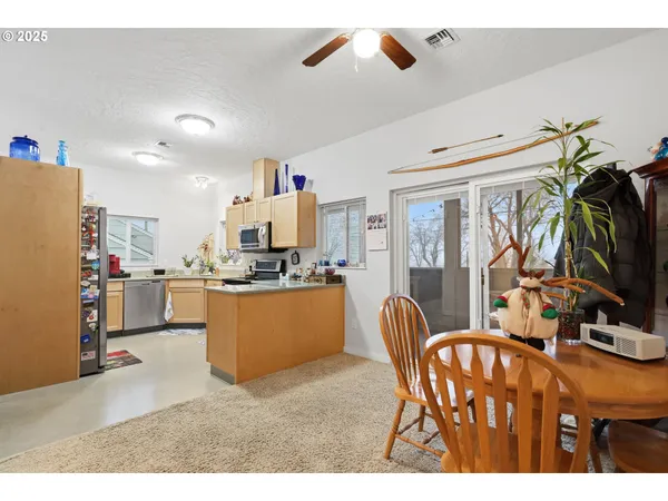 a kitchen with stainless steel appliances a refrigerator a stove a sink a dining table and chairs