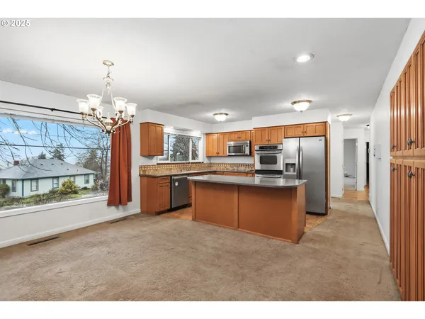 a kitchen with stainless steel appliances kitchen island granite countertop a refrigerator and a sink