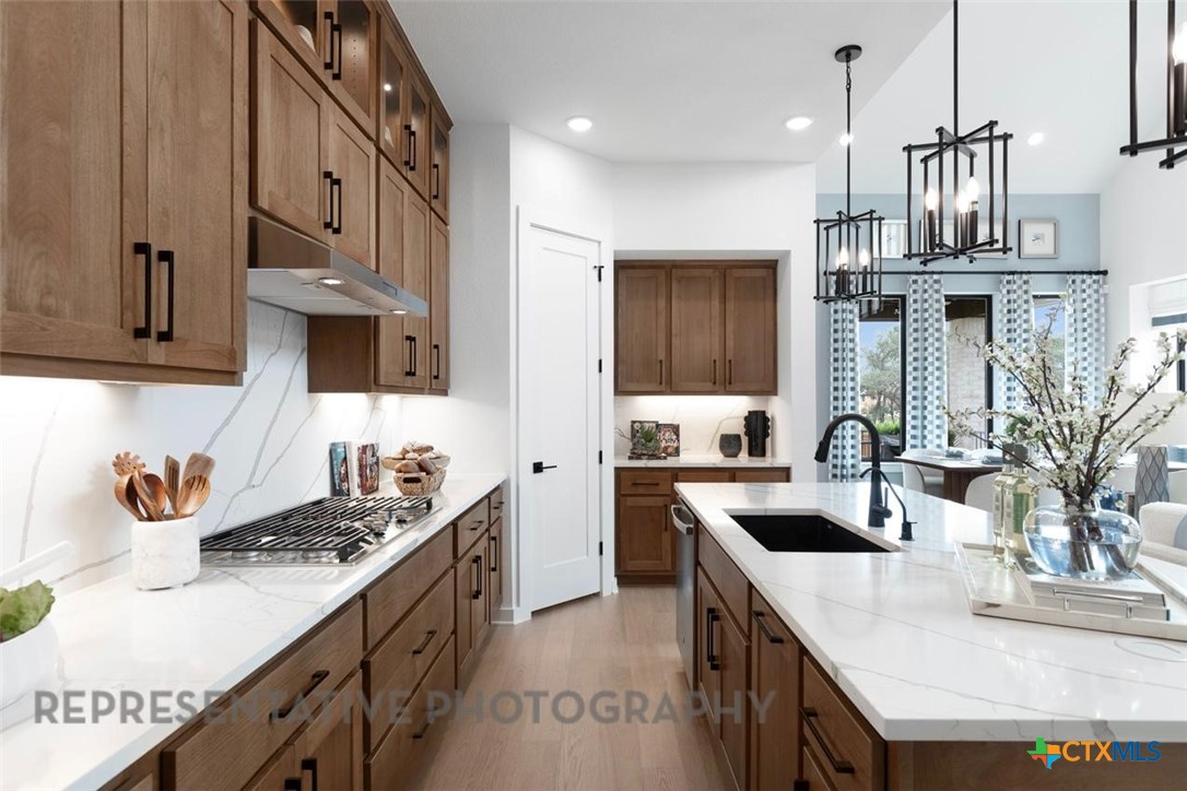 244 Basket Flower Loop Kyle, TX 78640 - Photo 5 of 34 a kitchen with stainless steel appliances granite countertop a sink a stove and a wooden cabinets