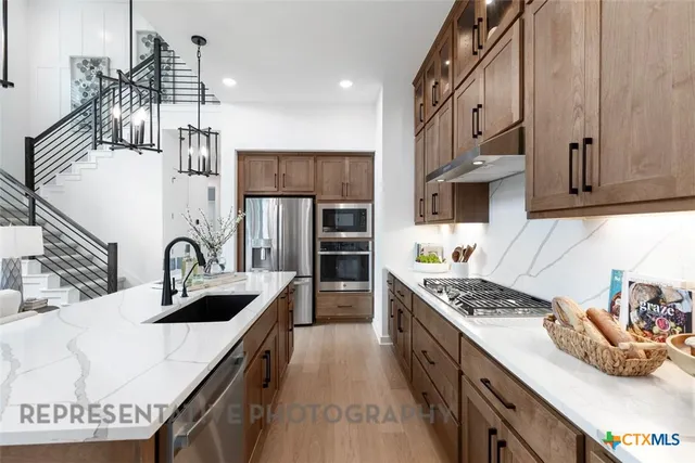 a kitchen with stainless steel appliances granite countertop a sink stove and refrigerator