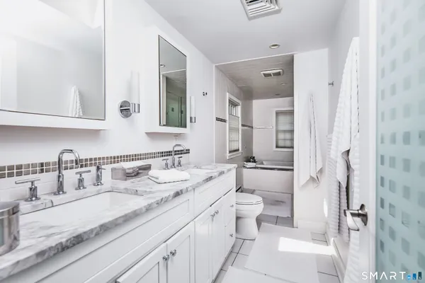 a bathroom with a granite countertop sink a toilet a mirror and shower