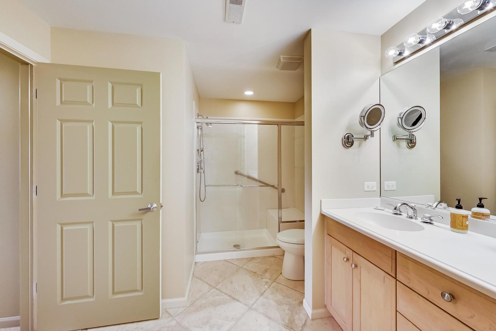 950 Augusta Way, Unit 204 Highland Park, IL 60035 - Photo 19 of 36 a bathroom with a shower sink vanity and mirror