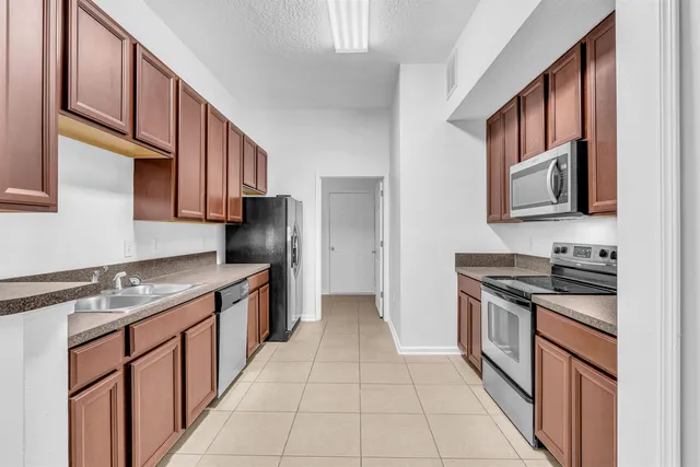 a kitchen with stainless steel appliances granite countertop a stove top oven a sink a refrigerator and dishwasher