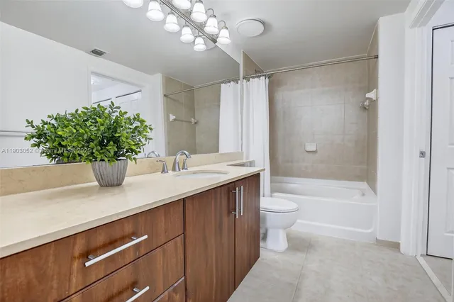 a bathroom with a granite countertop sink a toilet a large mirror and shower